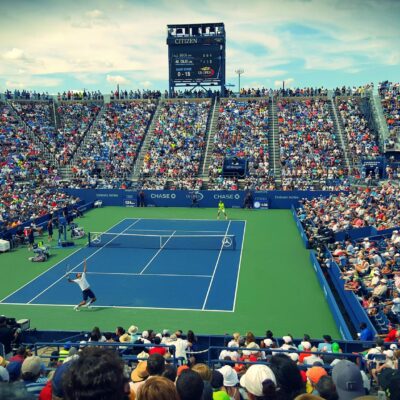 People Sitting on Bench Watching Tennis Event on Field during Daytime